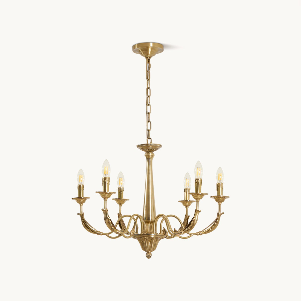 A brass candle-style Clérachic chandelier with six arms, a tapered column and a hanging chain, on a plain white backdrop.