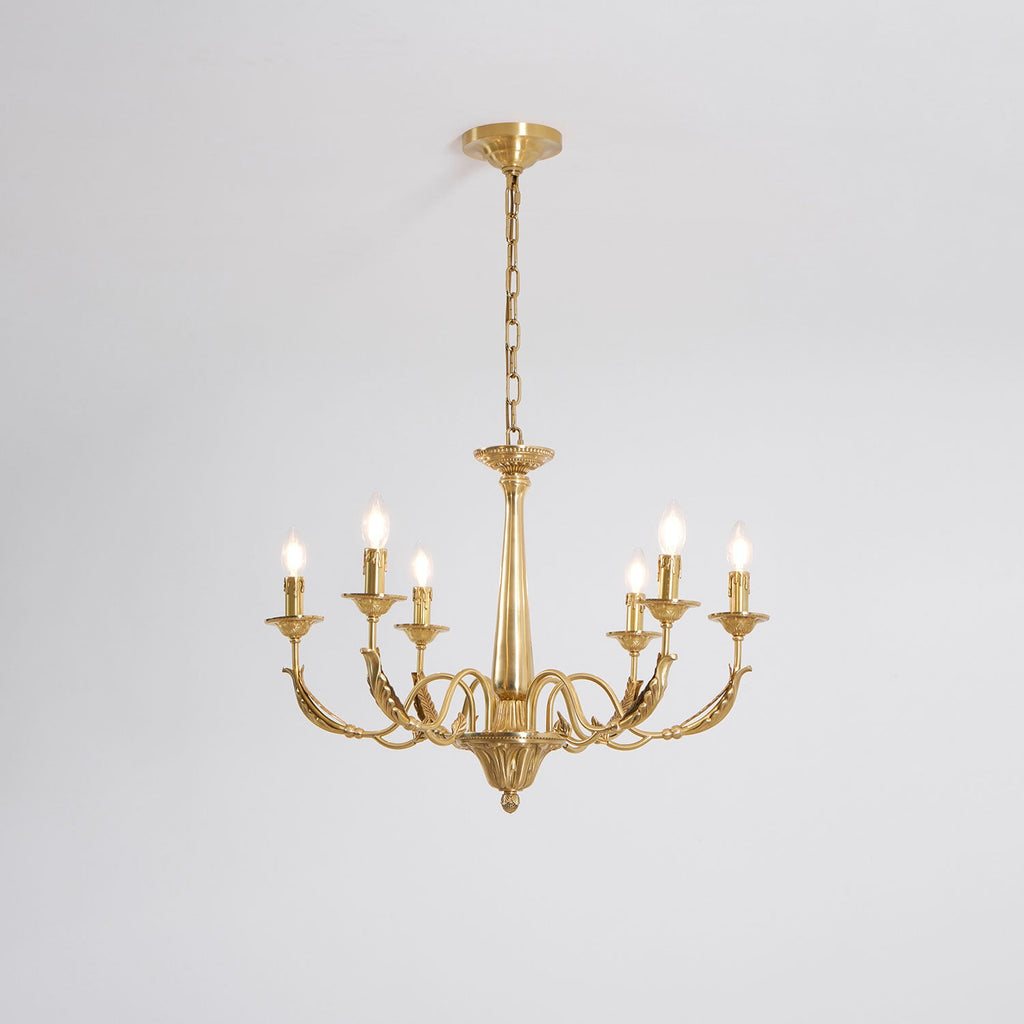 A brass candle-style Clérachic chandelier with six arms and tapered column, seen from slightly below on a pale grey backdrop.