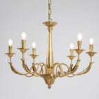 A brass Clérachic chandelier with six lit filament bulbs, curved leaf-detail arms and a tapered column, on a pale backdrop.