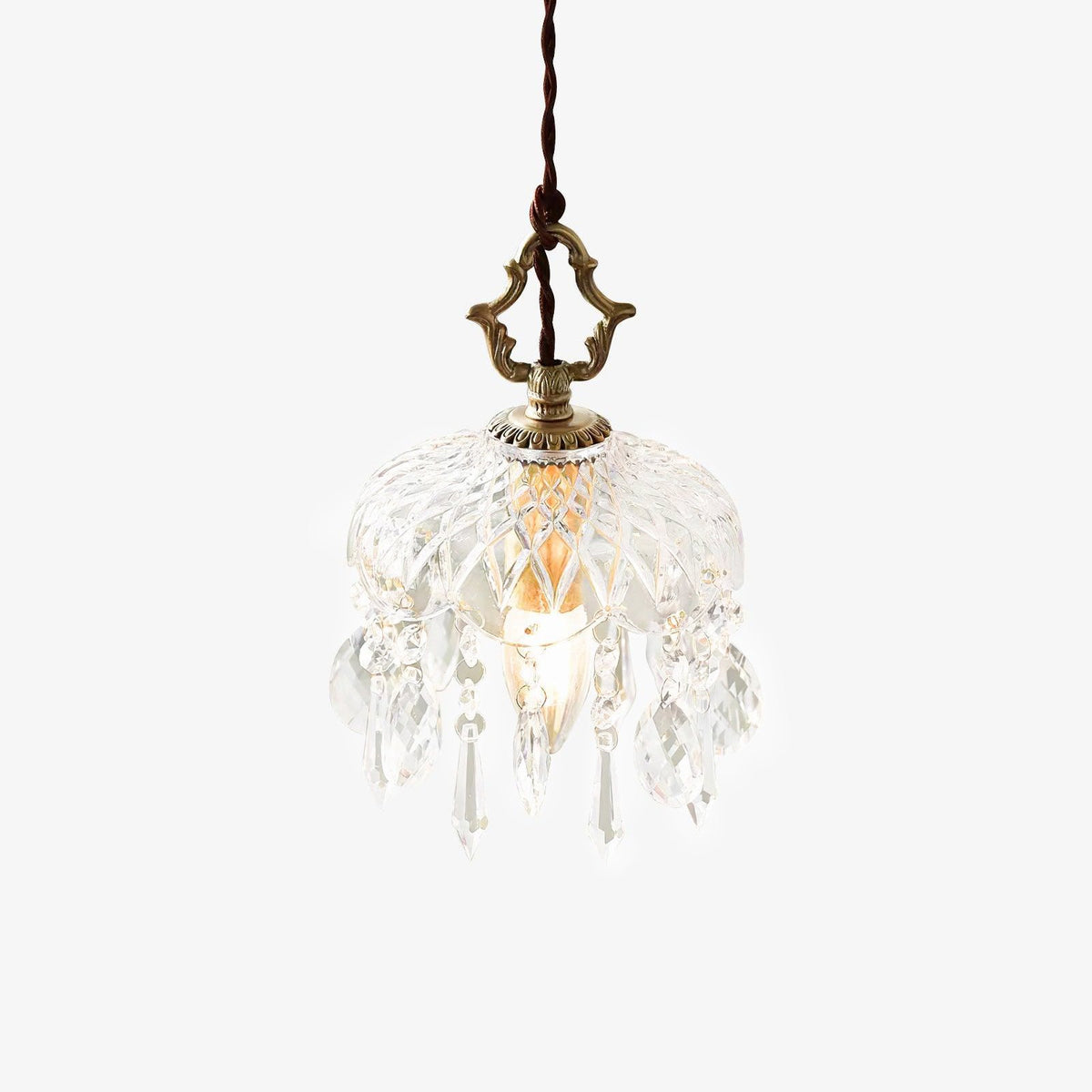 Cut-glass bowl pendant from Clérachic on a white backdrop, with hanging crystal drops, a brass top finial and a twisted dark cord.