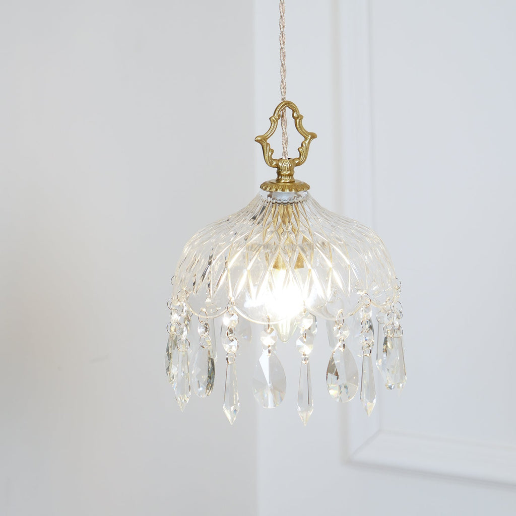 Clérachic pendant with a faceted glass bowl and a fringe of crystal drops, lit on a pale wall panel, hung from a pale twisted cord.