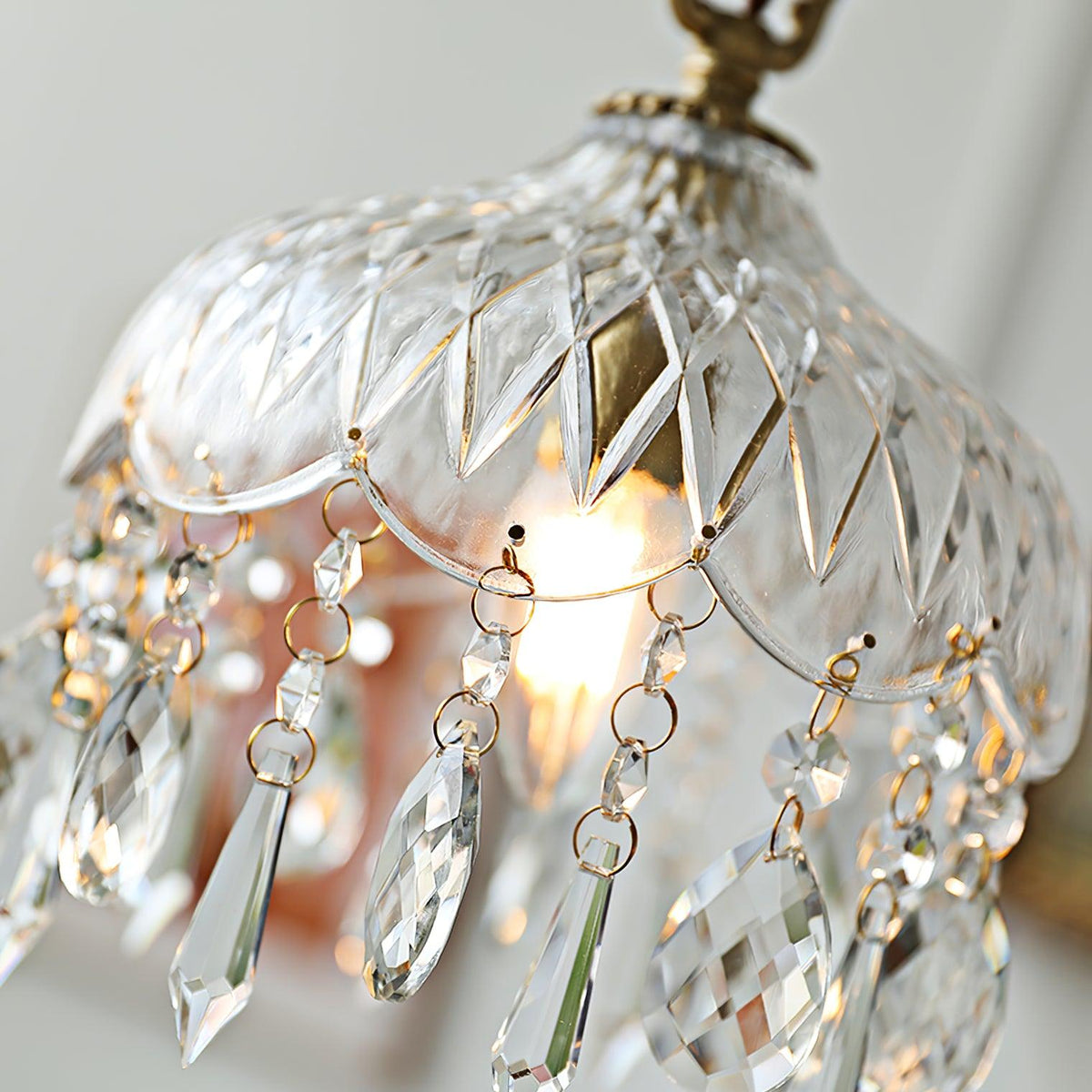 Close view of the diamond-cut glass bowl on this Clérachic pendant, with fine chain swags and cut crystal drops, lit from inside.