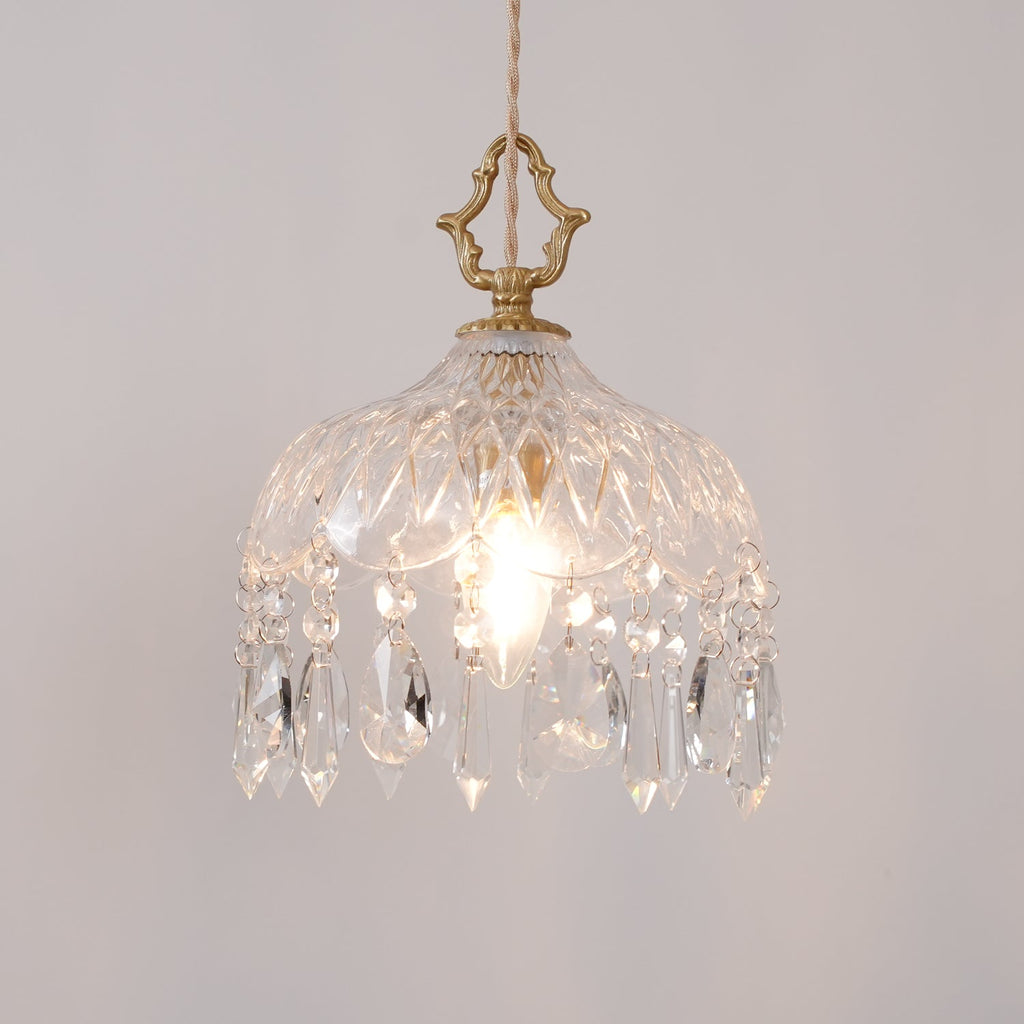 Clérachic cut-glass pendant lit on a light grey wall, with a brass crown finial and a fringe of long and short crystal drops.
