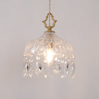 Clérachic cut-glass pendant lit on a light grey wall, with a brass crown finial and a fringe of long and short crystal drops.