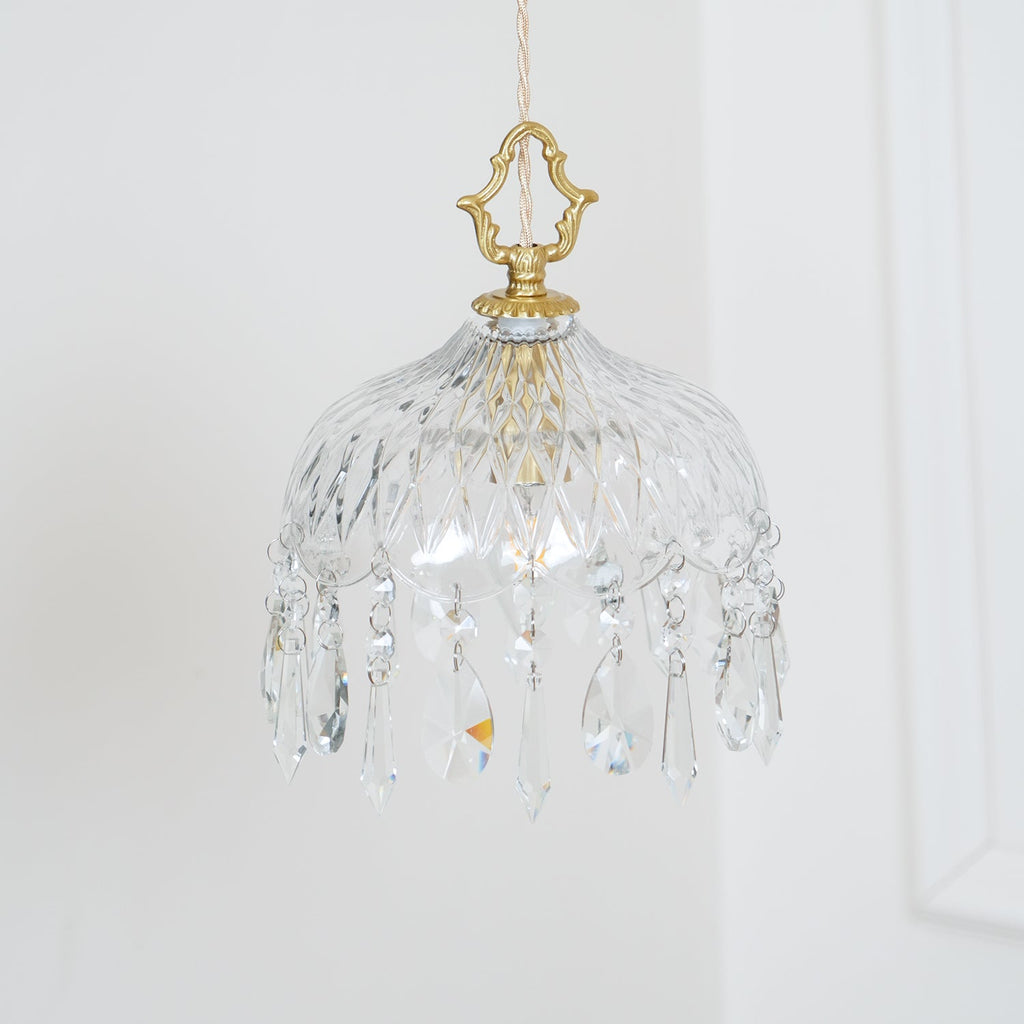 Clérachic cut-glass pendant on a pale wall, with a brass crown finial and a fringe of crystal drops of several shapes.