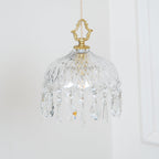 Clérachic cut-glass pendant on a pale wall, with a brass crown finial and a fringe of crystal drops of several shapes.