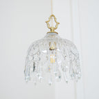 Clérachic crystal-drop pendant on a pale wall, with a diamond-cut glass bowl, a brass crown finial and rows of crystal drops.