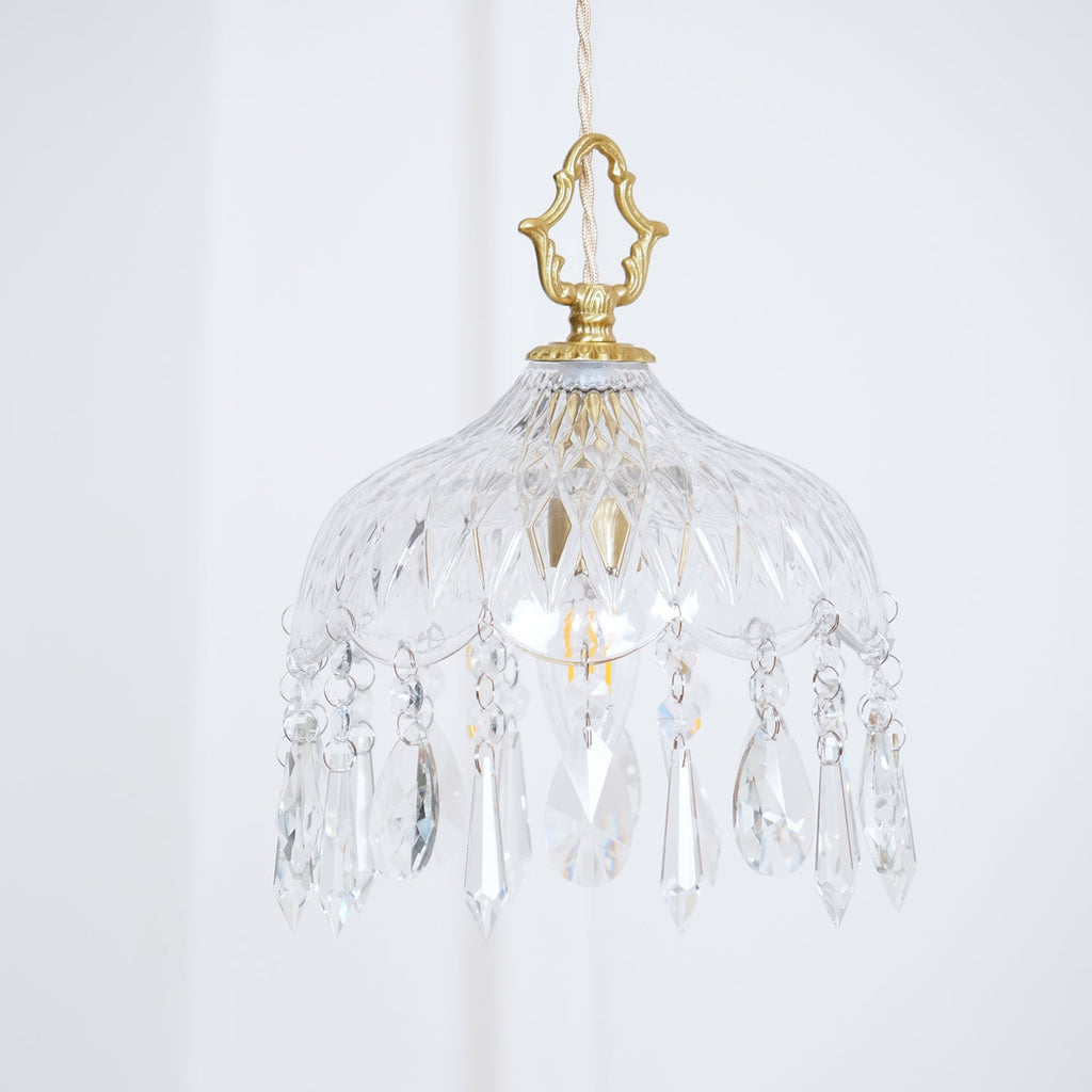 Clérachic crystal-drop pendant with a rounded glass bowl and a brass crown finial, with a framed colourful print below.