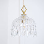 Clérachic crystal-drop pendant with a rounded glass bowl and a brass crown finial, with a framed colourful print below.