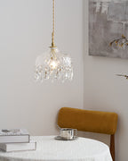 Clérachic crystal-drop pendant lit beside a grey abstract artwork, with bare branches, a mustard chair and a cream vase at the right.