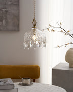 Close view of a lit Clérachic crystal-drop pendant with a diamond-cut glass bowl, beside bare branches and a cream vase.