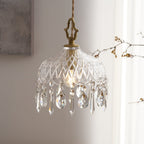 Clérachic crystal-drop pendant lit in a room with a grey artwork, branches, a yellow chair and a steel cup on a table below.