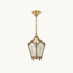 On a plain white backdrop, a Clérachic lantern pendant with an ornate brass frame, frosted glass panels and a slim hanging chain.
