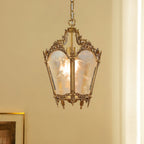 A lit Clérachic lantern pendant hangs in front of a cream curtain, with a gilt picture frame at the lower edge.