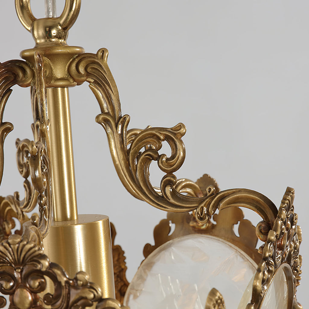 Close view of the carved brass scrolls and central stem at the top of this Clérachic lantern pendant, with frosted glass below.