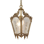 A Clérachic lantern pendant with a lit bulb, frosted glass panels and a carved brass frame, on a plain white backdrop.