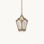 A small Clérachic lantern pendant with an ornate brass top, frosted panels and a thin chain, hanging on a pale cream backdrop.