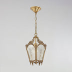A Clérachic lantern pendant with a brass canopy, a chain and frosted glass panels hangs against a soft grey backdrop.