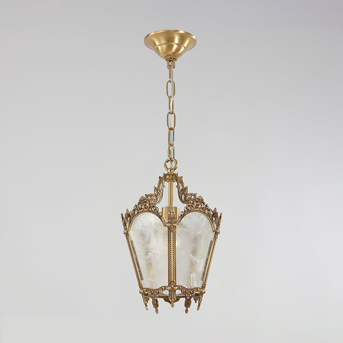 A Clérachic lantern pendant with a brass canopy, a chain and frosted glass panels hangs against a soft grey backdrop.
