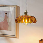 Lit amber Clérachic pendant on a twisted cord, beside a framed print of a woman in a pink dress.