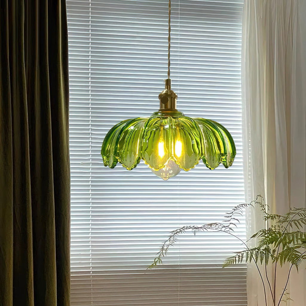 Green glass Clérachic pendant in front of a window with blinds and olive curtains, with a fern at the lower right.