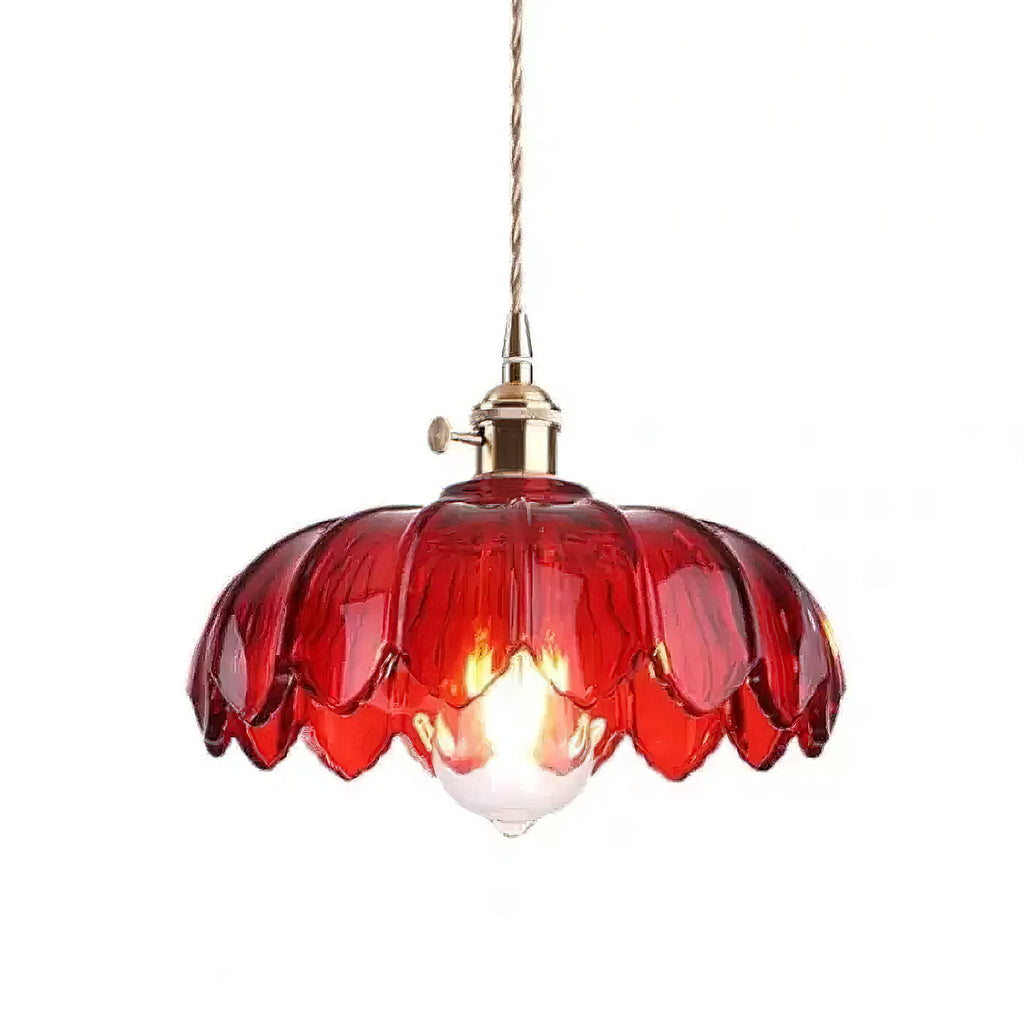 Red glass Clérachic pendant with a brass fitting and a lit bulb, on a plain white backdrop.