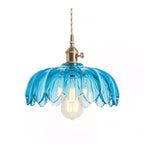 Blue glass Clérachic pendant with a petal-edged shade, a brass switch fitting and a warm bulb, on a plain white backdrop.