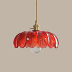 Red glass Clérachic pendant, with ribbed petals and a clear bulb, hanging from a twisted cord on a taupe backdrop.