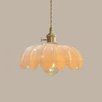 White glass Clérachic pendant with a petal-edged shade glowing a soft warm cream, on a taupe backdrop.