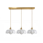 Row of three white glass Clérachic pendants hanging from one long brass ceiling bar on a white backdrop.