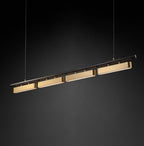 A four-head Clérachic linear pendant on a dark backdrop, its brass diffusers lit along the underside of a slim black bar.