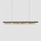 A four-head Clérachic linear pendant on a plain light grey backdrop, with brass diffusers under a slim black bar.