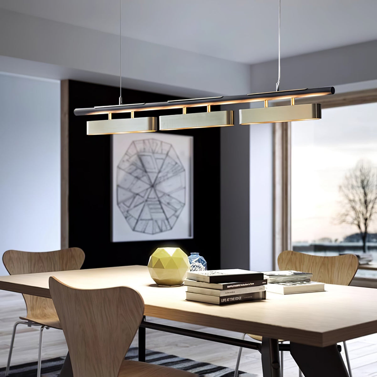Clérachic three-head pendant above a wooden dining table with moulded chairs and a large window onto bare winter trees.