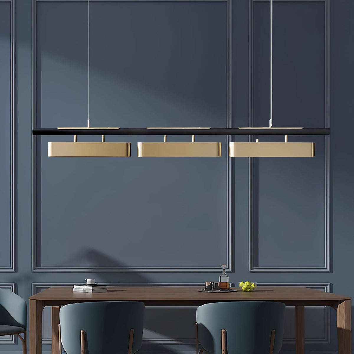 Three-head Clérachic brass pendant on a navy panelled wall, hung above a wooden table with dark green chairs.