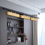 Close view of this Clérachic brass pendant above a wine shelf and cream curtains, its black bar angled across the frame.