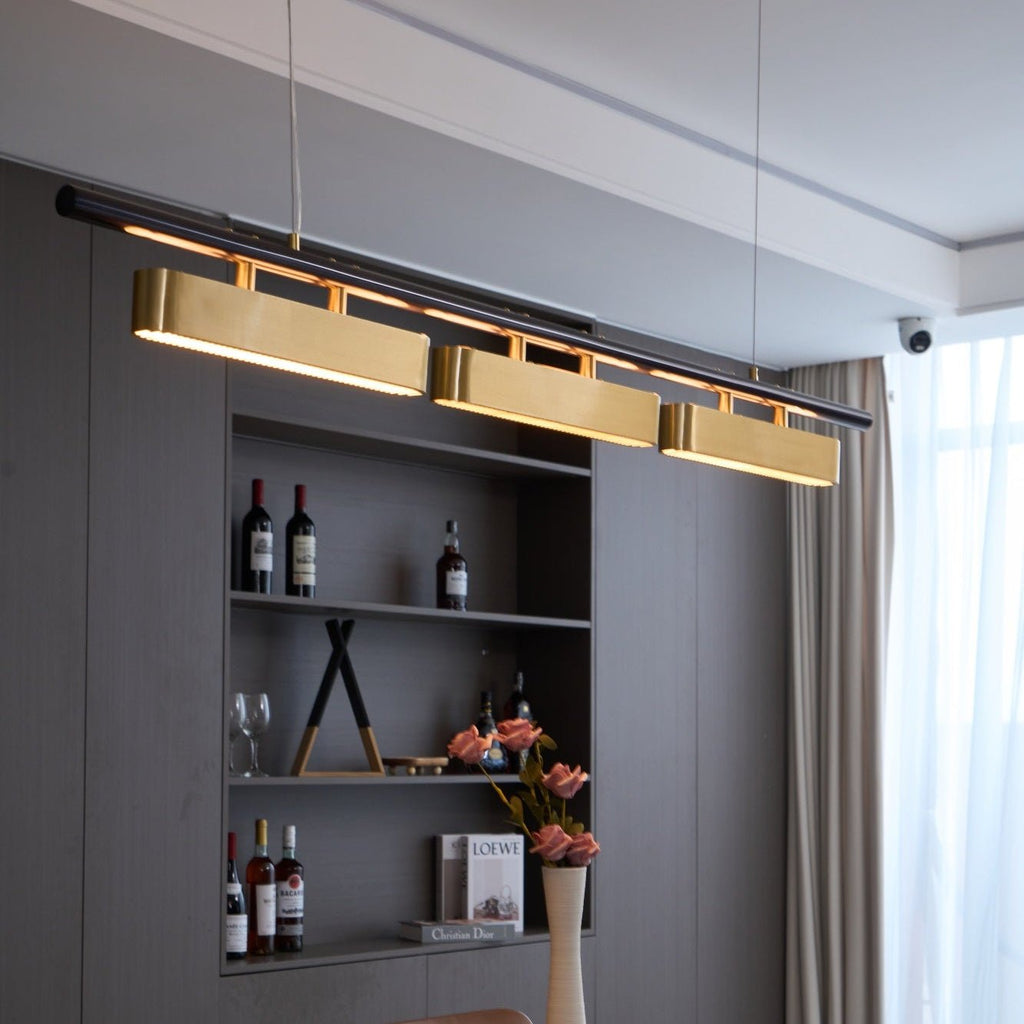 Close, low view of the lit Clérachic pendant, with warm light along the black bar above each brass diffuser.