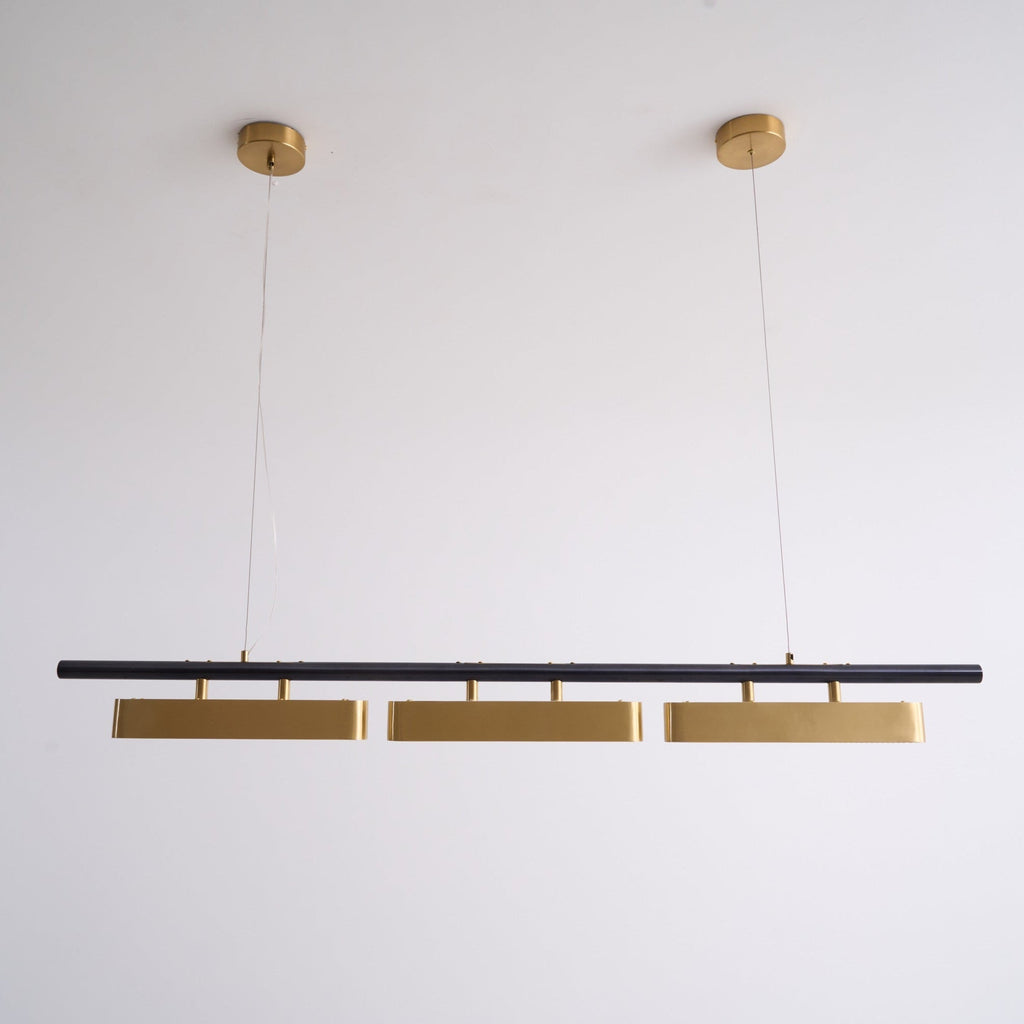 Unlit Clérachic three-head pendant on a white wall, hung from two round brass canopies on thin wires.