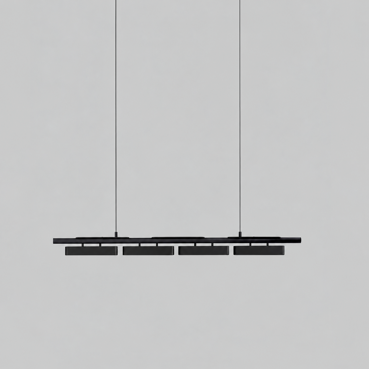 All-black Clérachic linear pendant with four heads, hung on thin wires against a light grey backdrop.