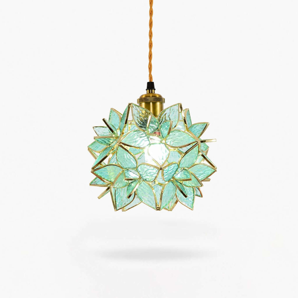A Clérachic pendant light with a green glass petal shade, a brass socket and a braided cord, shown on a plain white backdrop.