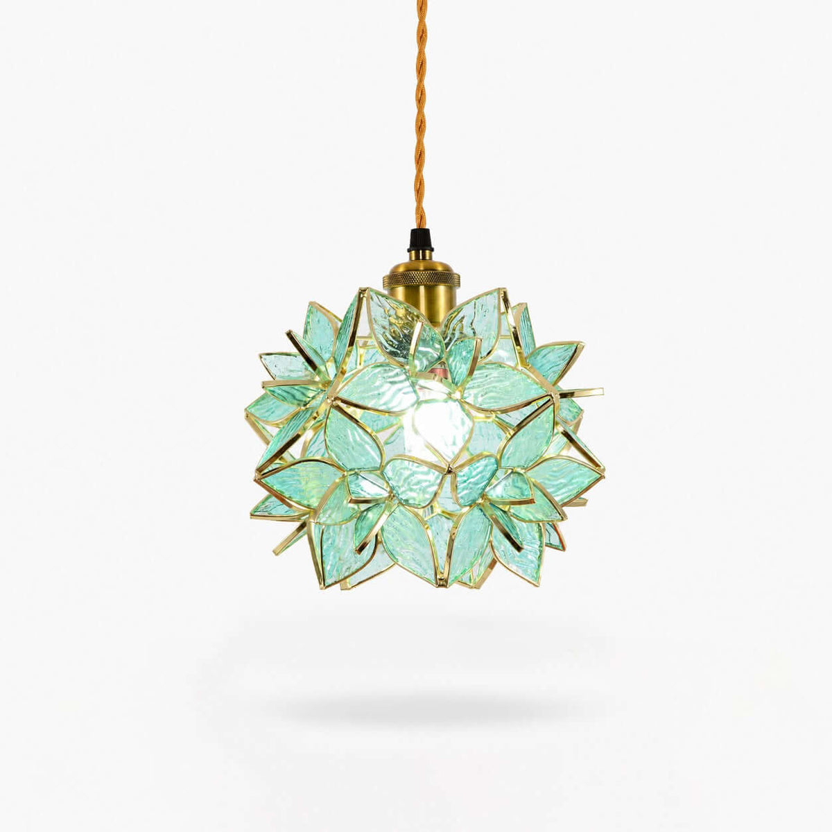 A Clérachic pendant light with a green glass petal shade, a brass socket and a braided cord, shown on a plain white backdrop.