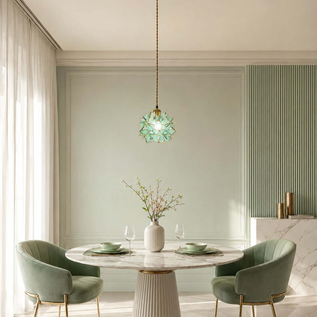 This Clérachic pendant with a green glass petal shade hangs over a round marble table and two sage velvet chairs.
