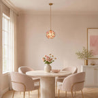 This Clérachic pendant with a pink petal shade hangs above a round pale table with blush chairs, in a window-lit dining corner.