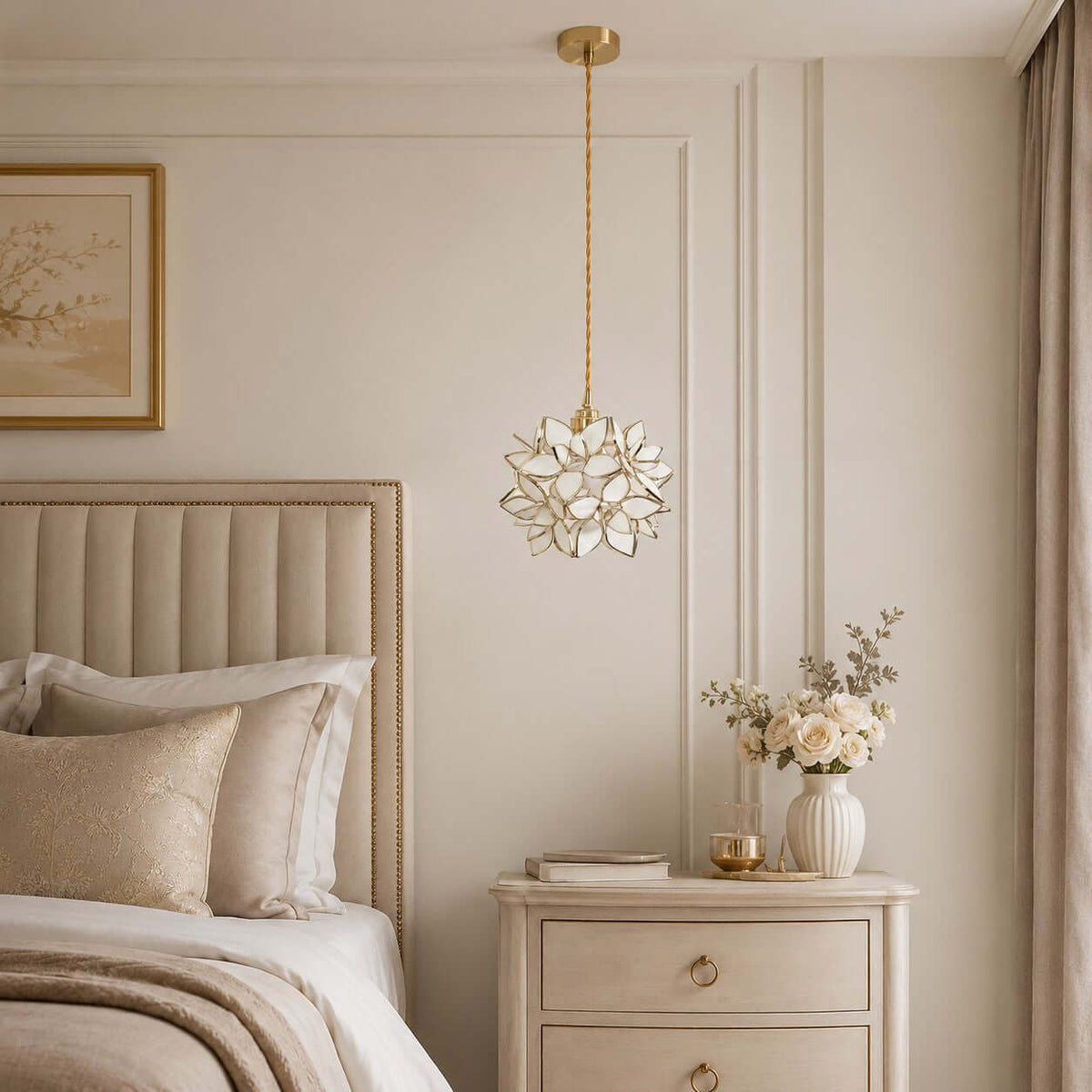 A white petal Clérachic pendant with fine gold edging hangs above a bedside chest, in front of a ribbed headboard.