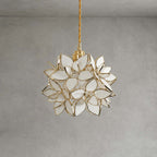 A Clérachic pendant with white glass petals edged in gold, shown unlit on a braided cord against a grey wall.