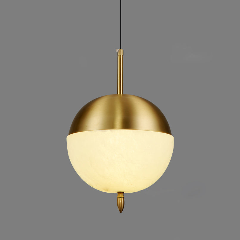 Clérachic Brass Pendant Light as a split globe: brushed brass cap, glowing Spanish alabaster half, pointed brass finial.