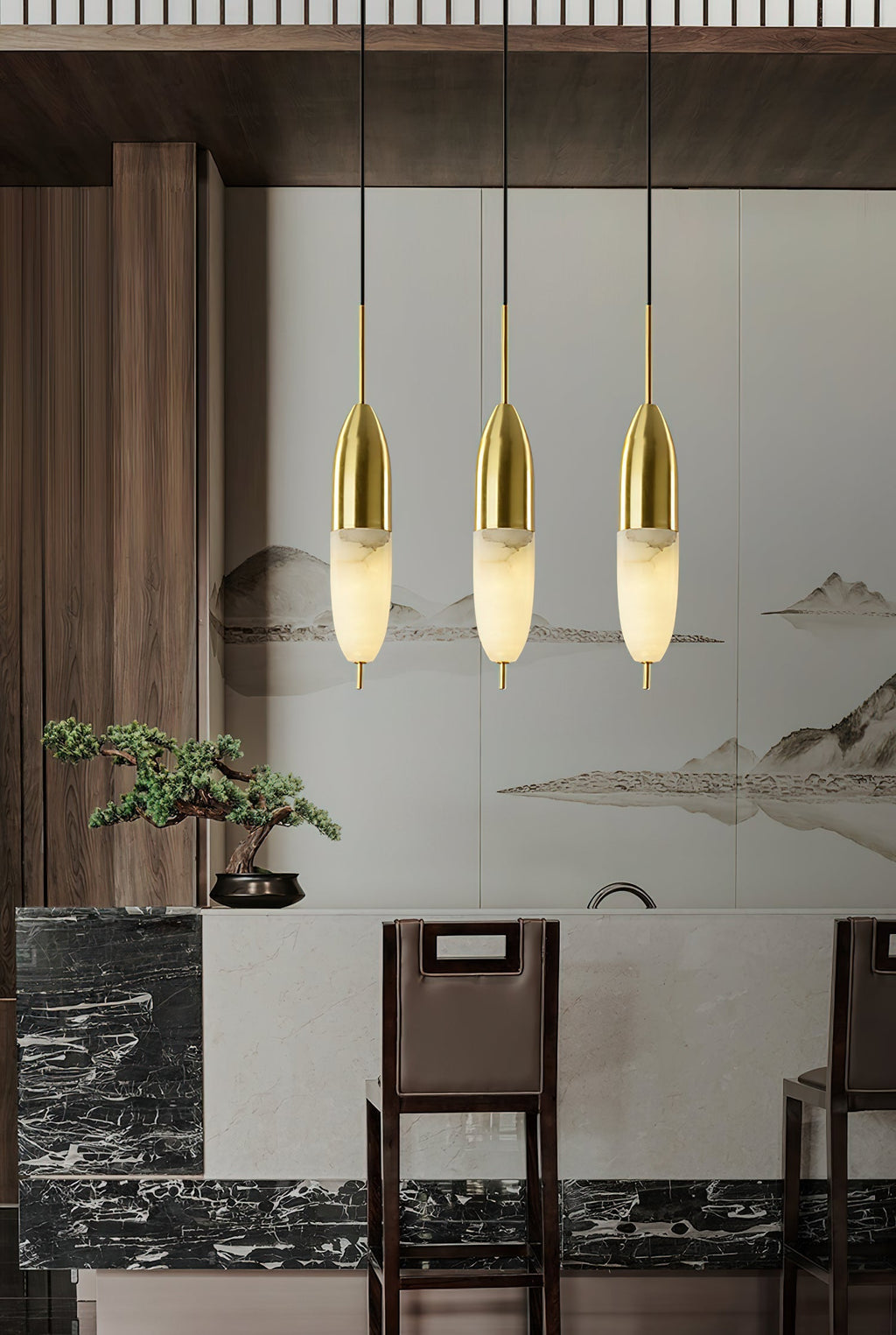Clérachic Brass Pendant Lights hung in a row over a marble bar, dark wood stools, and a mountain-ink mural.