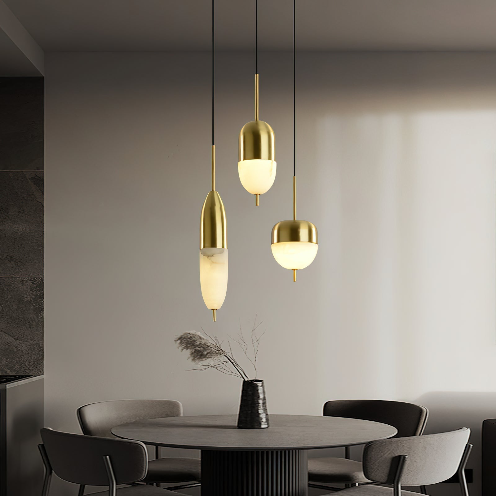 A Clérachic Brass Pendant Light trio — tall, mid, and wide — over a charcoal round dining table with grey chairs.