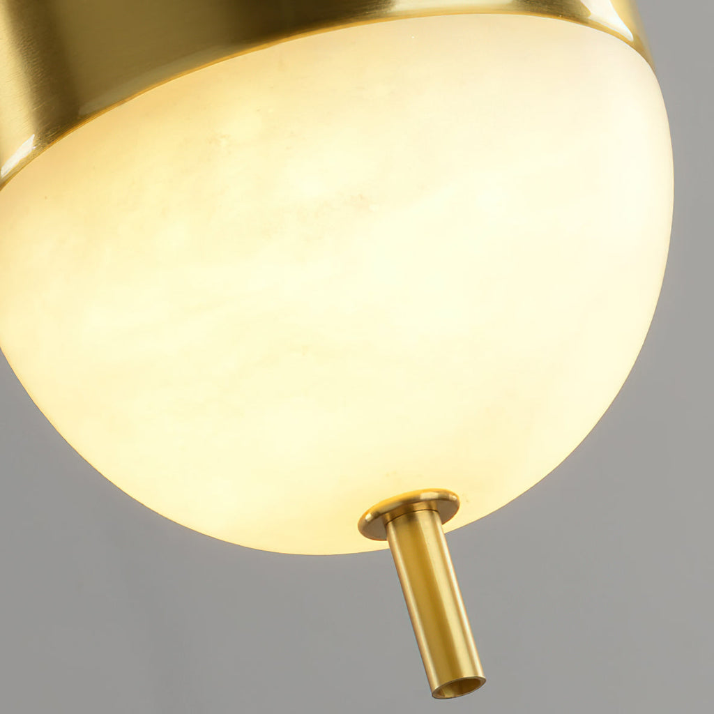 Lit Spanish alabaster globe on the Clérachic Brass Pendant Light, brass cap above and a small brass cylinder at the base.