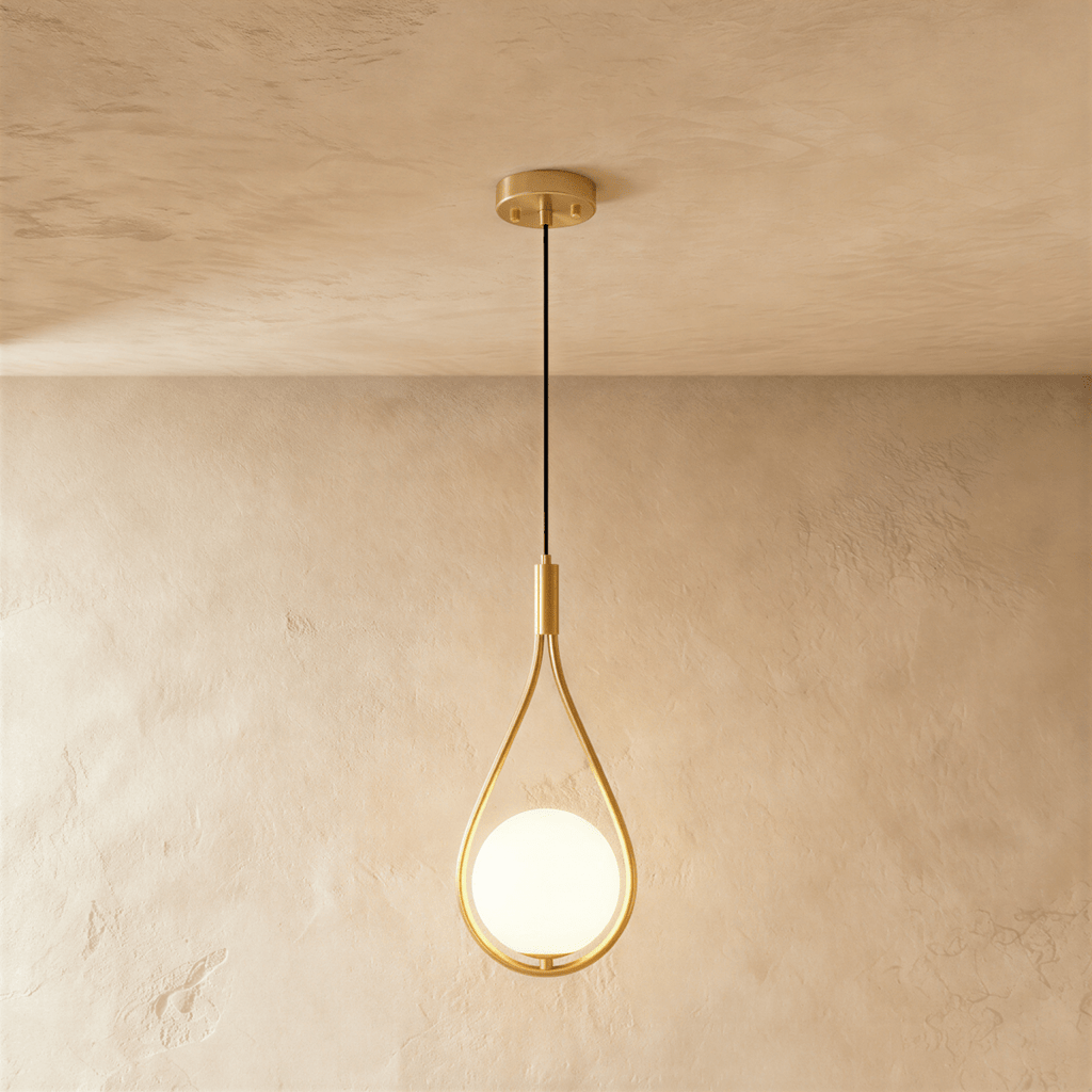 Clérachic brass teardrop wire pendant holding a glowing opal glass globe, hung on a black cord from a round brass ceiling plate.