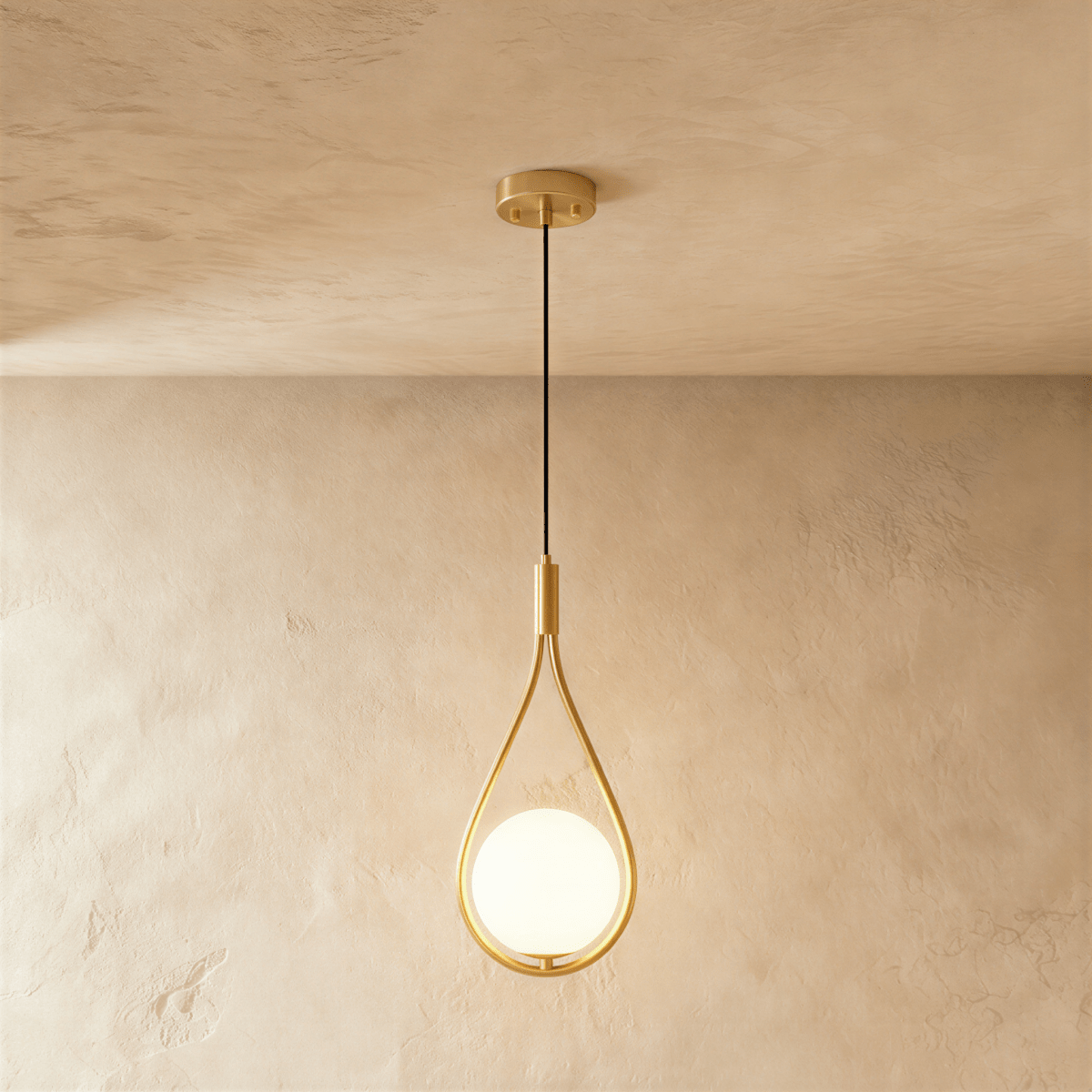 Clérachic brass teardrop wire pendant holding a glowing opal glass globe, hung on a black cord from a round brass ceiling plate.